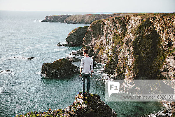 Mann steht am Rande einer Klippe über dem malerischen Meer  Bedruthan Steps  Cornwall  UK
