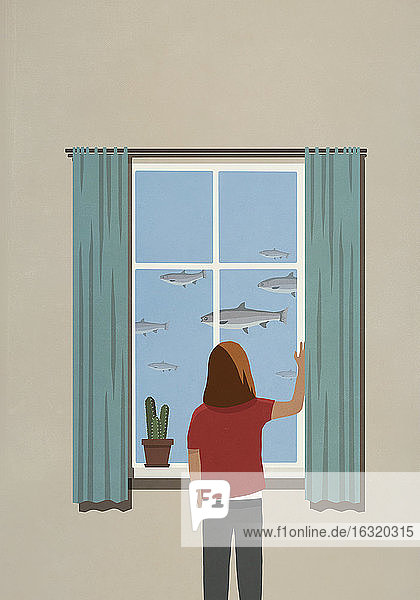Frau betrachtet schwimmende Fische vom Fenster aus