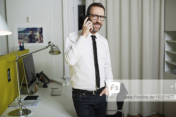 Lächelnder Geschäftsmann beim Telefonieren im Büro