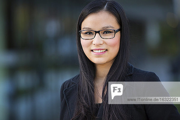 Porträt einer lächelnden jungen Geschäftsfrau mit Brille