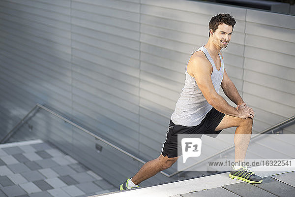 Sportsman doing stretching exercises on a staircase