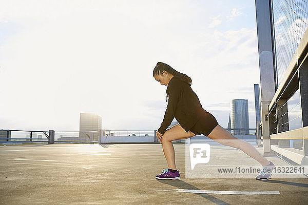 Young female Asian sportswoman doing stretching exercises