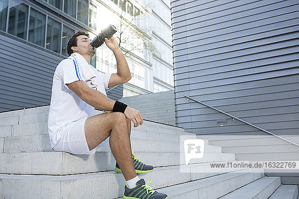 Sportler macht eine Pause und trinkt aus seiner Flasche