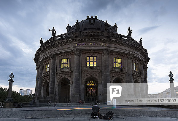 Deutschland  Berlin  Blick auf das beleuchtete Bode-Museum auf der Museumsinsel mit Straßenmusikanten im Vordergrund
