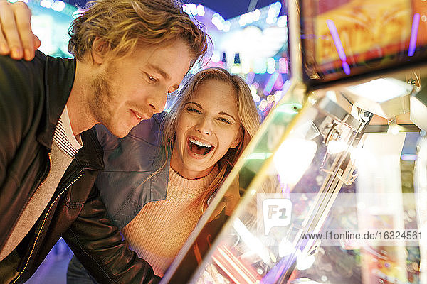 Young couple at fun fair looking at prizes in window