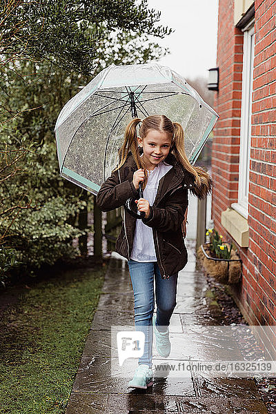 Porträt eines lächelnden Mädchens mit Regenschirm an einem regnerischen Tag