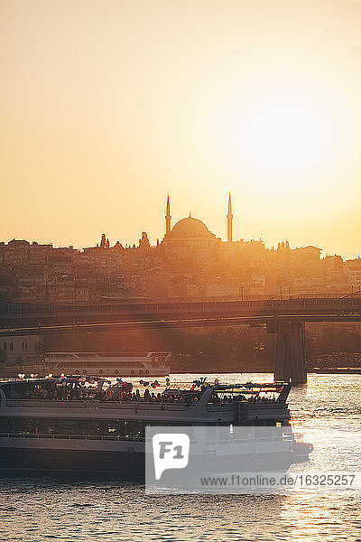 Türkei  Istanbul  Blick auf Fährschiff auf dem Bosporus mit Silhouette der Moschee bei Sonnenuntergang
