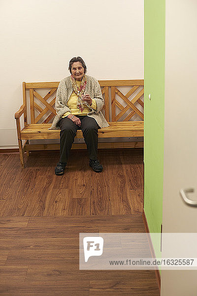 Age demented senior woman sitting on bench in a nursing home