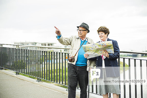 Älteres Paar mit Karte auf einer Brücke stehend