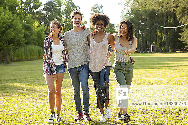 Glückliche junge Freunde gehen zusammen im Park spazieren