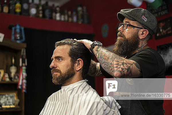Hairdresser styling man's hair in salon