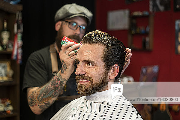 Friseurin stylt Haare eines Mannes im Salon