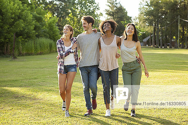 Glückliche junge Freunde gehen zusammen im Park spazieren