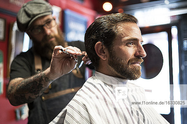 Hairdresser cutting man's hair in salon