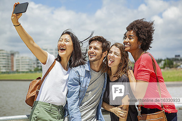 Happy young friends taking selfie on smartphone