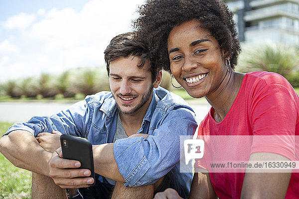 Junges Paar benutzt Smartphone im Park