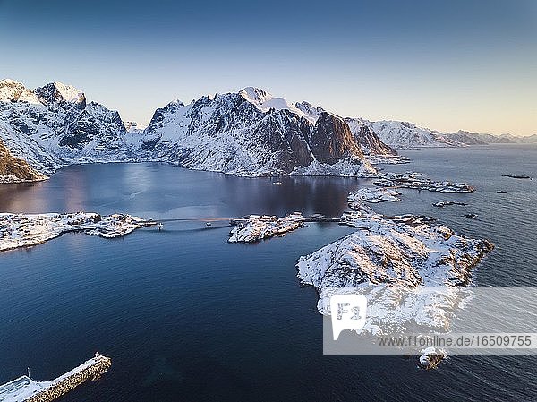 Luftaufnahme  Fjordlandschaft bei Sonnenaufgang  verschneite Berge im Winter  Fischerdorf Reine  Reine  Nordland  Lofoten  Norwegen  Europa