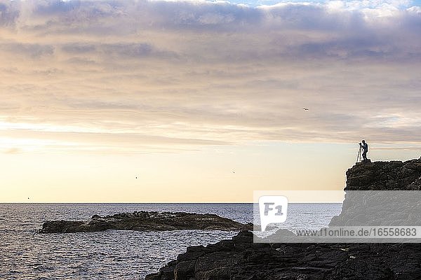 Landschaftsfotograf Silhouette an der dramatischen Küste  Fotografieren des Meeres  County Antrim in Nordirland