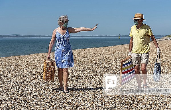 Southsea  Portsmouth  Südengland  UK. Mai 2020. Eine Frau trägt eine chirurgische Maske und distanziert sich während des Corvid-19-Ausbruchs von ihrem Mann. Am Strand von Southsea  Vereinigtes Königreich.