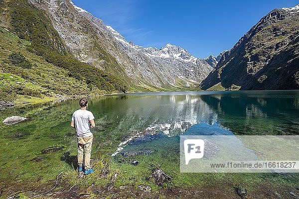 Hiker stands on shore  Lake Marian  Fiordland National Park  Te Anau  Southland  South Island  New Zealand  Oceania