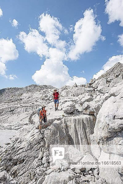 Zwei Wanderer in einer Landschaft aus ausgewaschenen Karststeinfelsen  Funtenseetauern  Steinernes Meer  Nationalpark Berchtesgaden  Berchtesgadener Land  Oberbayern  Bayern  Deutschland  Europa