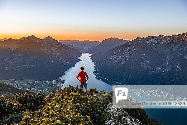Sonnenuntergang  junger Mann blickt über Berglandschaft  Ausblick vom Gipfel des Bärenkopf auf den Achensee  links Seebergspitze und Seekarspitze  rechts Rofangebirge  Tirol  Österreich  Europa