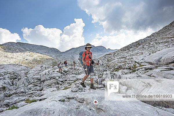 Vier Wanderer in einer Landschaft aus ausgewaschenen Karststeinfelsen  Funtenseetauern  Steinernes Meer  Nationalpark Berchtesgaden  Berchtesgadener Land  Oberbayern  Bayern  Deutschland  Europa
