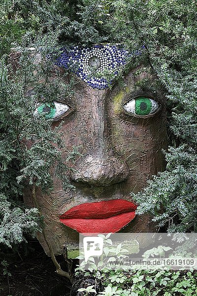 Magical woman face with red lips and green eyes looks through branches sculpture sculpture garden by the artist Jochen Bach Plinzmühle Plinz Großkröbitz Milda Thuringia Germany Europe