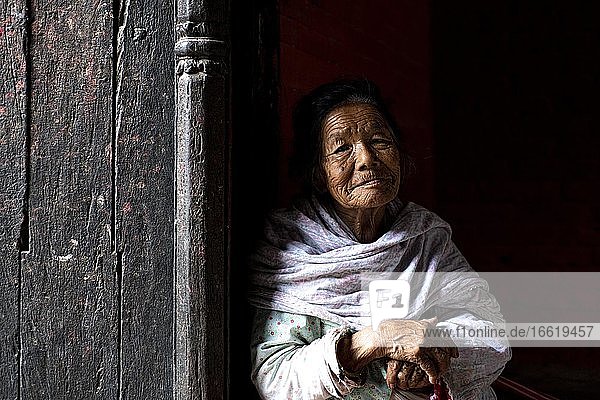 Porträt einer älteren Frau die aus einer Türöffnung herausschaut  Patan  Lalitpur  Kathmandu  Nepal  Asien