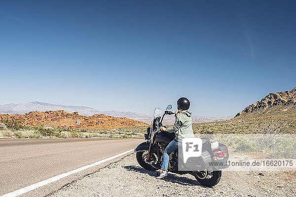Woman riding motorcycle during summer road trip  Nevada  USA
