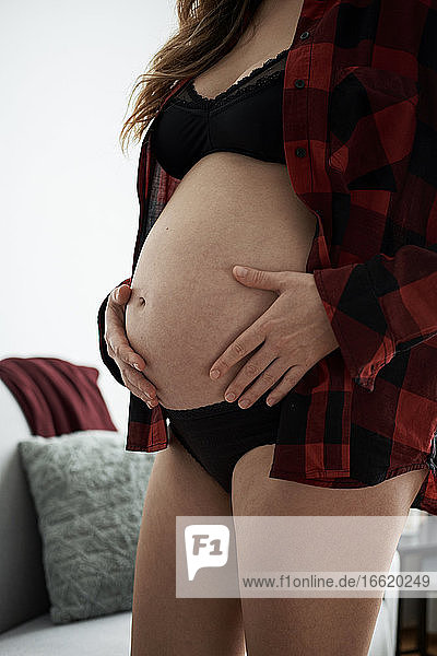 Nahaufnahme einer schwangeren Frau  die ihren Bauch berührt  während sie zu Hause steht