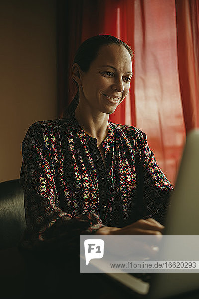 Geschäftsfrau lächelnd bei der Arbeit am Laptop im Büro