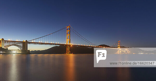 Illuminated Golden Gate Bridge over sea against clear sky at San Francisco  California  USA