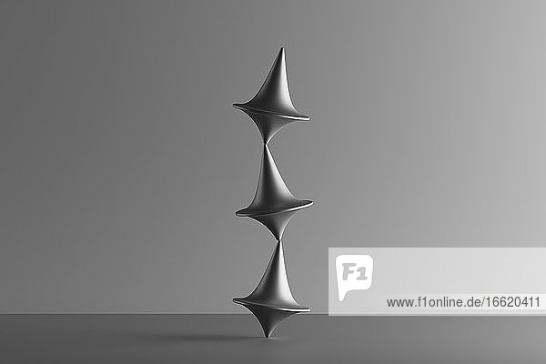 Dreidimensionales Rendering von drei übereinander balancierenden Metallkreiseln