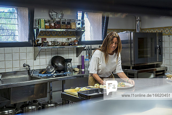 Selbstbewusste Diätassistentin bei der Zubereitung einer Mahlzeit in einer Großküche