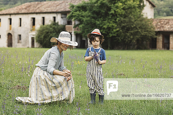 Mutter und Sohn sammeln Blumen auf einer Wiese