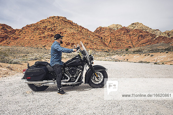 Man sitting on motorcycle at Valley of Fire State Park  Nevada  USA