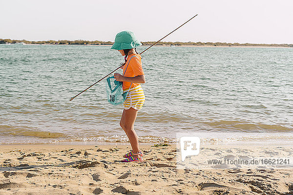 Kleines Mädchen sammelt Plastikmüll vom Strand