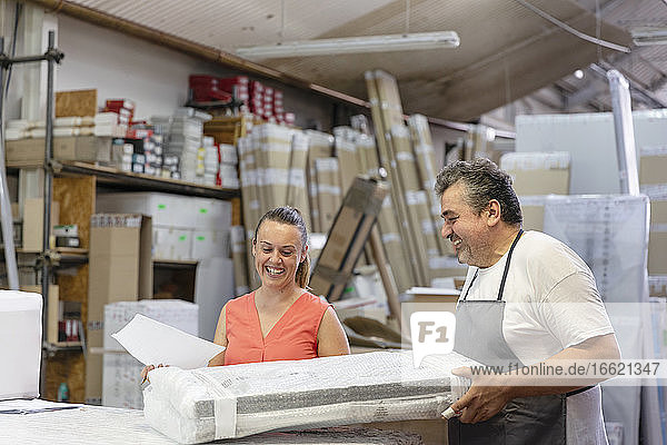 Lächelnde Mitarbeiterin und Sekretärin bei der Arbeit im Stehen in einer Fabrik