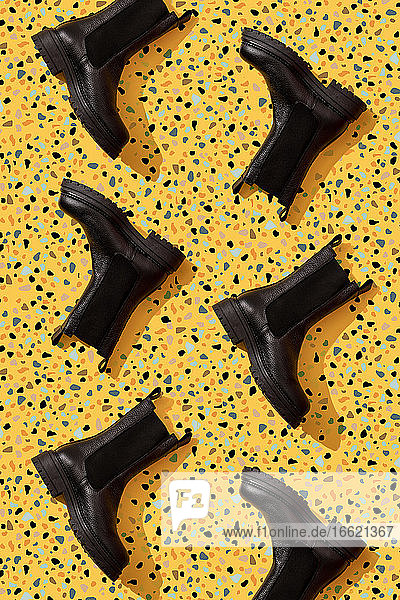 Black leather boots on yellow terrazzo pattern