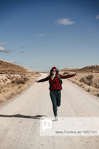 Spanien  Navarra  Weibliche Touristin  die auf einem leeren Feldweg in Bardenas Reales in Richtung Kamera läuft