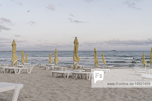 Sonnenschirme und Liegestühle am leeren Strand in der Abenddämmerung