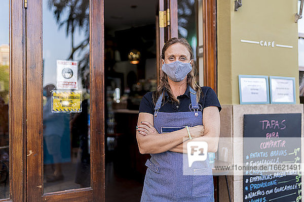 Confident female cafe owner wearing protective face mask during COVID-19 outbreak