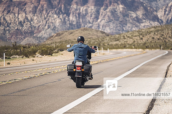 Man riding motorcycle on desert road  Nevada  USA