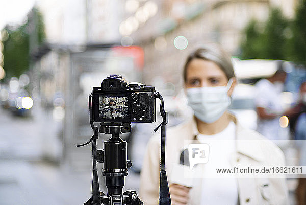 Journalistin mit Maske filmt mit Kamera in der Stadt