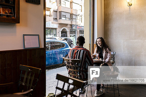 Glückliche junge Frau mit Freund im Café