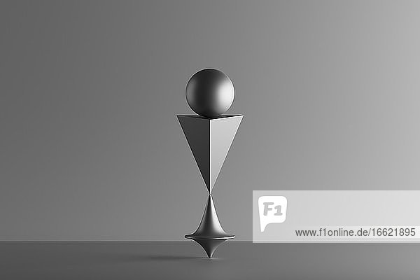 Dreidimensionales Rendering eines sich drehenden Metallkreisels unter einer geometrischen Pyramide und einer Kugel