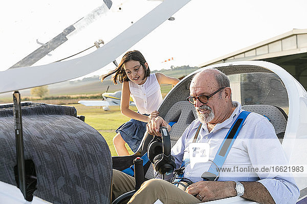 Junges Mädchen im Cockpit eines Flugzeugs mit Großvater auf dem Flugplatz
