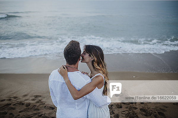 Girlfriend kissing boyfriend while standing at beach