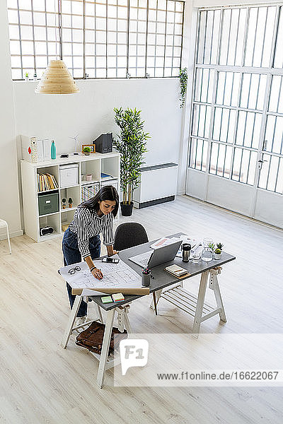 Selbstbewusste Geschäftsfrau arbeitet an einem Entwurf am Schreibtisch in einem kreativen Büro